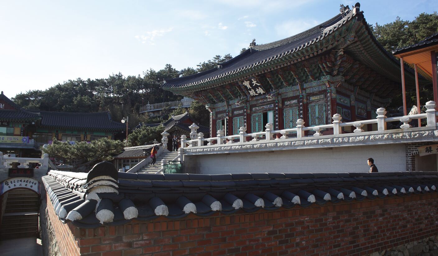 The main hall of Haedong Yonggungsa, its painted eaves and hanja name plaque above a white stone balustrade